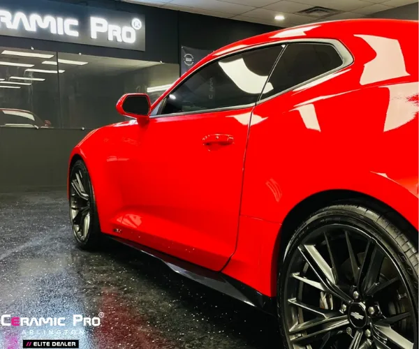 A side profile of a bright red sports car with black multi-spoke wheels