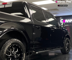 A side profile view of the black SUV, highlighting the uniform dark window tint and the mirror-like reflections on the clean door panels.